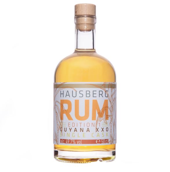 Eine Flasche Hausberg Rum Guyana XXO der Edition 1 mit weißem Etikett und Holzgriff-Verschluss auf transparentem Hintergrund. Der Inhalt der Flasche erscheint bernsteinfarben.

Auf dem Etikett ist in großer Schrift der Markenname dargestellt. 

Der Alkoholgehalt ist unten im Etikett mit 49,7 Volumenprozenten abgebildet. Daneben die Füllmenge mit 50 cl. 