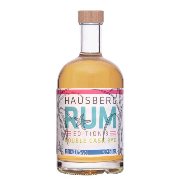 Eine Flasche Hausberg Rum Double Cask 3YO der Edition 3 mit weißem Etikett und Holzgriff-Verschluss in Vorderansicht auf transparentem Hintergrund. Der Inhalt der Flasche erscheint gold-braun.

Auf dem Etikett ist in großer Schrift der Markenname dargestellt. 

Der Alkoholgehalt ist unten im Etikett mit 43,0 Volumenprozenten abgebildet. Daneben die Füllmenge mit 50 cl. 